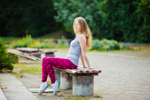 Young girl sitting on the bench in the park