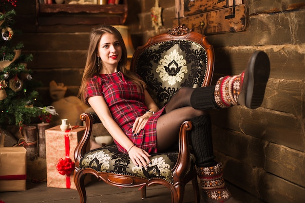 Young girl sitting next to Christmas tree and gifts