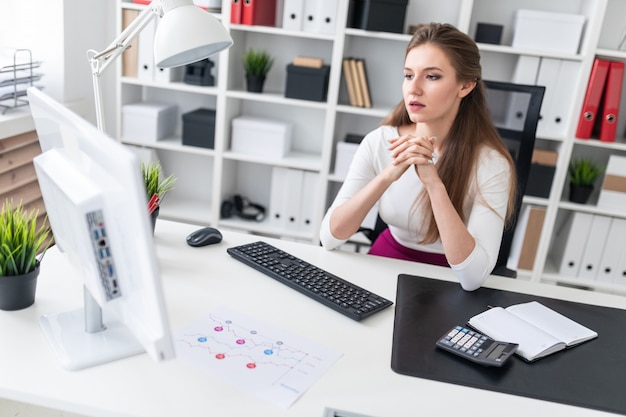 Una giovane ragazza seduta a una scrivania del computer e lavorare con i documenti.