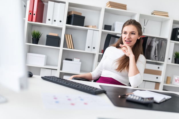 A young girl sitting at a computer Desk and working with documents.