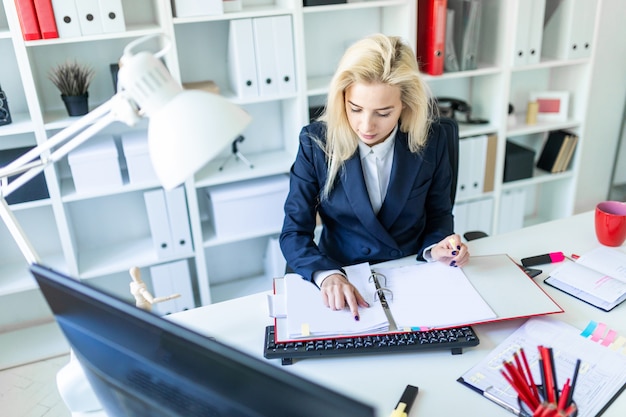 Photo young girl sitting at desk in office and working with documents.