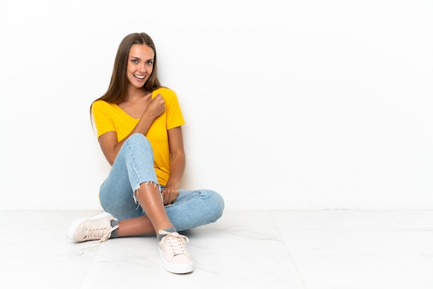 Giovane ragazza seduta sul pavimento per celebrare una vittoria