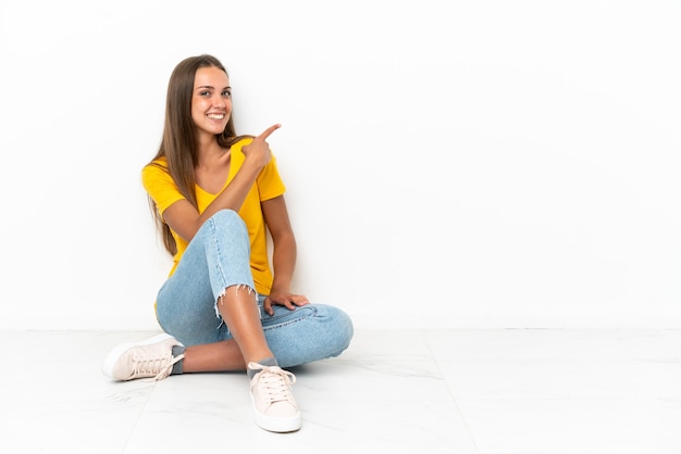 Ragazza che si siede sul pavimento che indica indietro