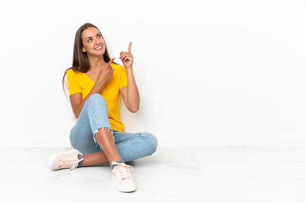 Young girl sitting on the floor pointing with the index finger a great idea