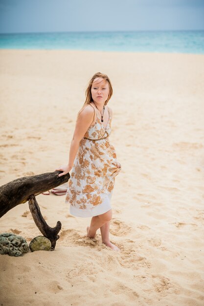 Young girl sitting on an old tree on the beach of Boracay