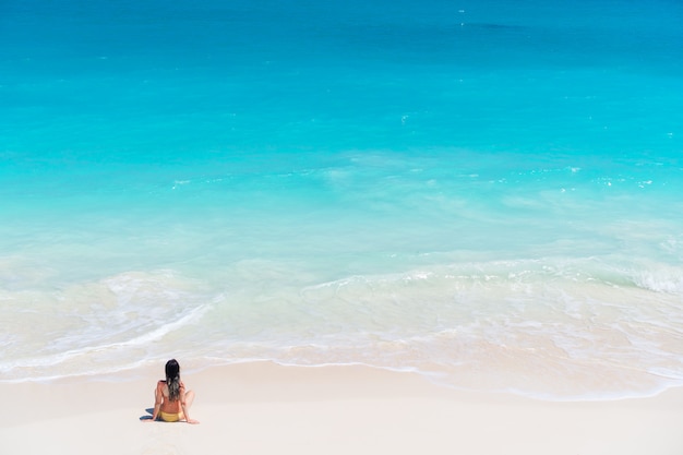 Ragazza che si siede in riva al mare