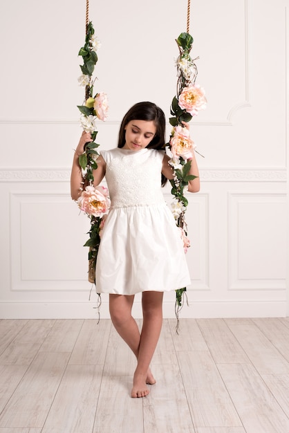 Young girl sitting on swing in spacious room