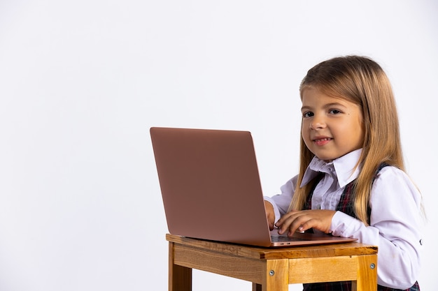 Photo young girl sitting at the table at home working on her homework from school typing out an answer on