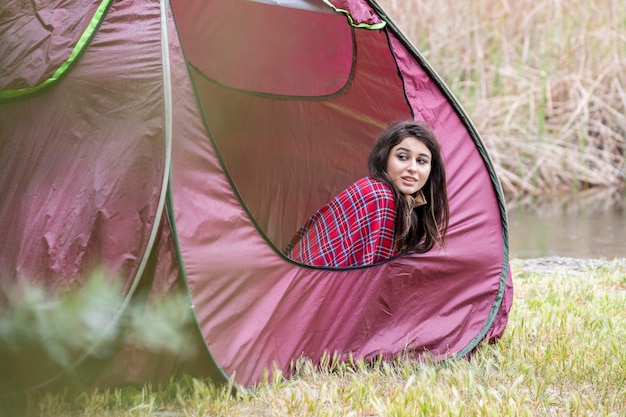 Молодая девушка сидит в палатке и смотрит в сторону