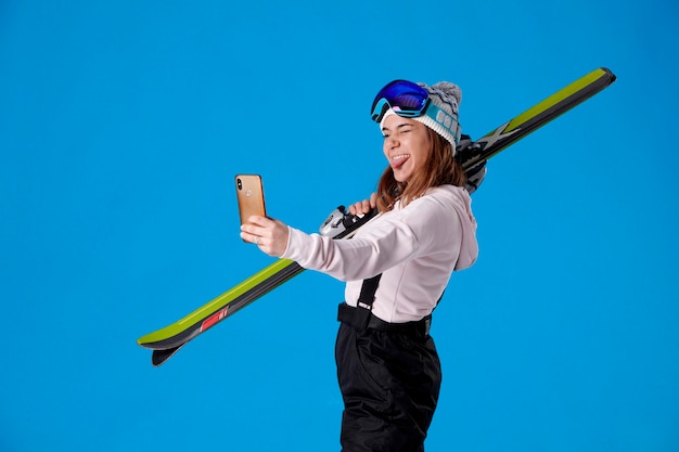 Young girl on skis taking a selfie winking and sticking her tongue out