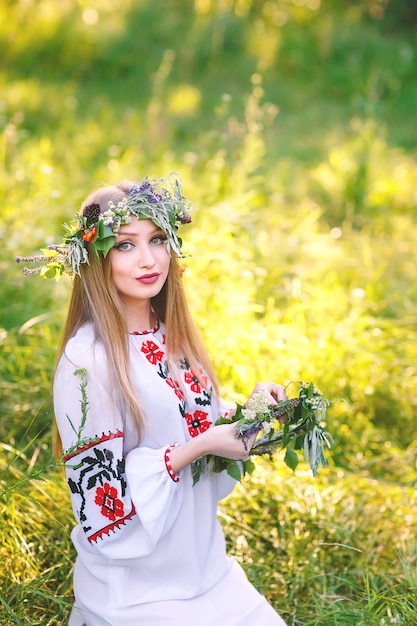 Una ragazza di aspetto slavo con una ghirlanda di fiori selvatici a metà estate.