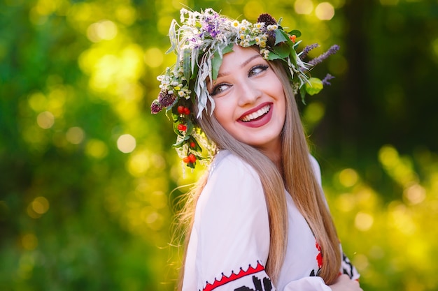 MidSummerに野生の花の花輪を持つスラブの外観の少女。