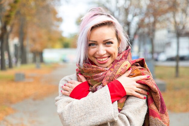 A young girl smiles and wraps herself in a scarf.