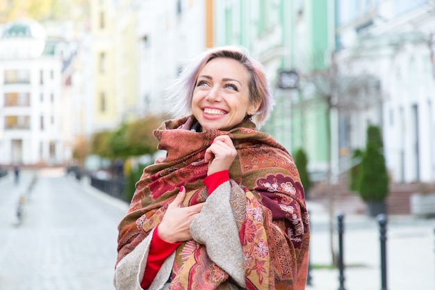 Photo a young girl smiles and wraps herself in a scarf.