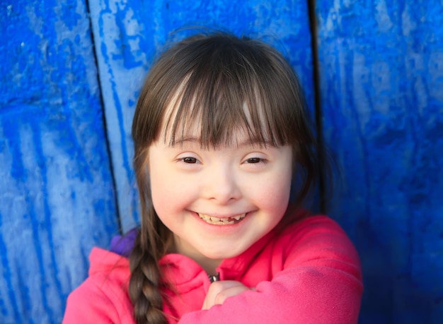 Молодая девушка улыбается на фоне синей стены