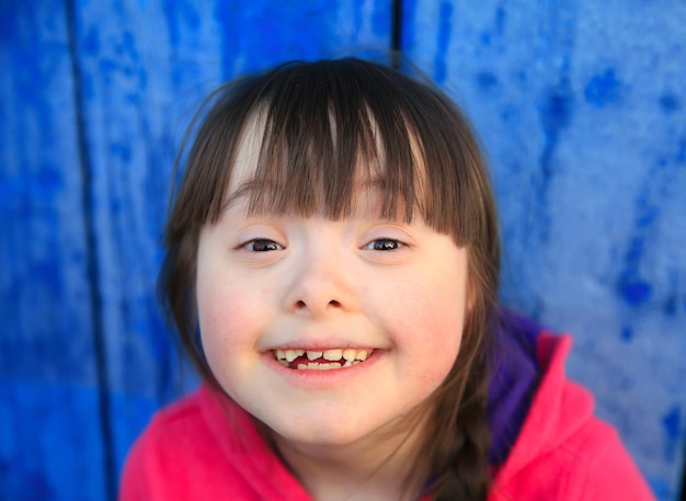 파란 벽을 배경으로 웃고 있는 어린 소녀.