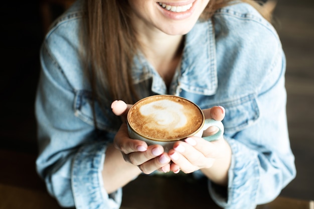 笑顔でおいしいコーヒーを飲む若い女の子