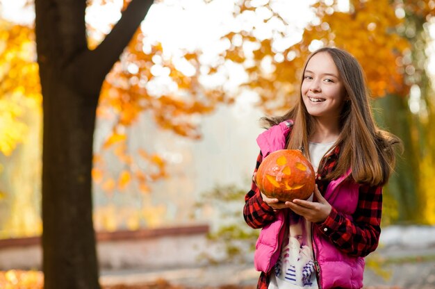 Young girl smiling joyfully with a pumpkin in her hands