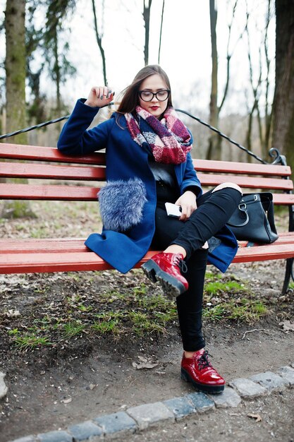 Young girl smoking cigarette outdoors sitting on bench Concept of nicotine addiction by teenagers