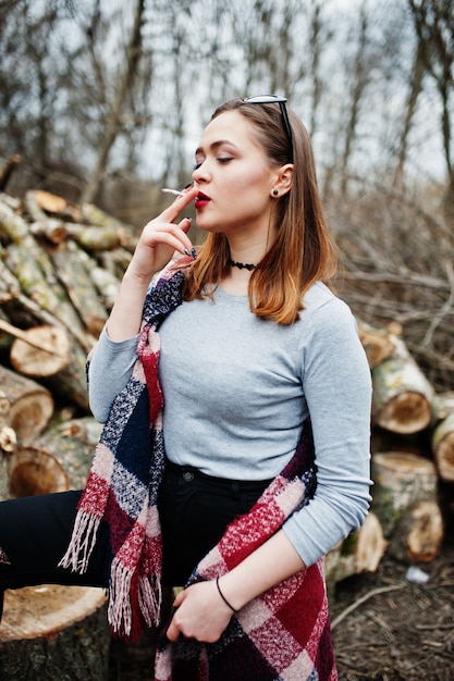 Молодая девушка курит сигарету на открытом воздухе