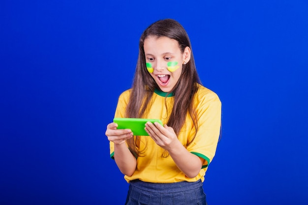 Young girl soccer fan from Brazil holding cellphone surprised Smartphone applications