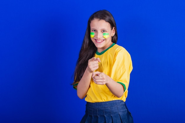 당신을 선택하는 카메라를 가리키는 브라질의 어린 소녀 축구 팬