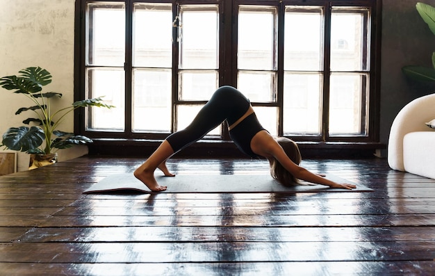 A young girl in sportswear does yoga fitness at home sports at home stretching