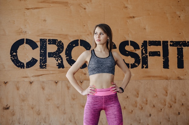 Young girl in sportswear in a gym in a simple background, a theme of fitness, a crossfit and sport