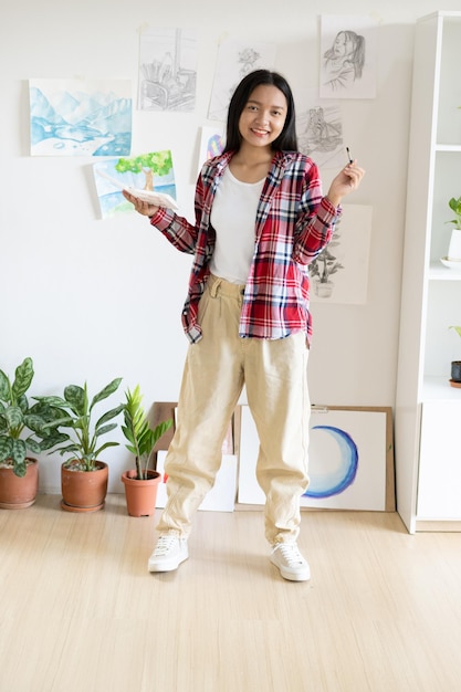 Young girl standing on the floor and hold Color palette and brush at room Hobby and art study at home