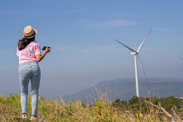 Young girl standing on the mountain taking beautiful landscape view and the Wind Turbine at Khao Yai Thieng Electric Wind Turbine Thailand