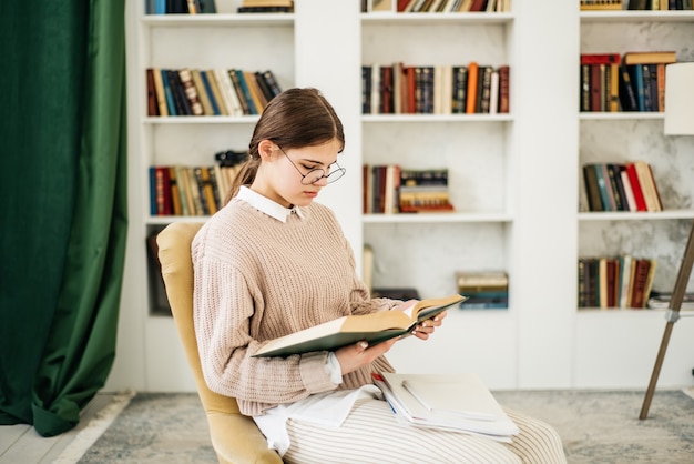 Young girl standing near the bookshelf in library