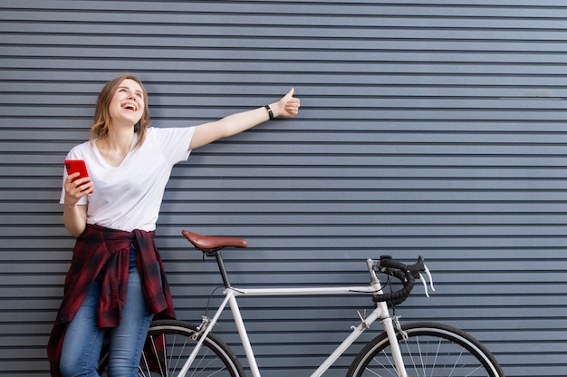 Young girl standing with a bicycle near a wall