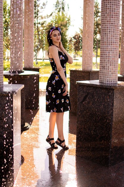 A young girl stands by the fountain on a hot summer day.