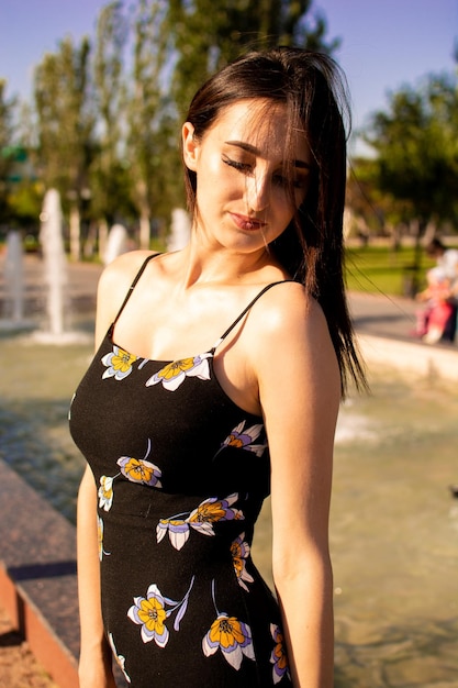 A young girl stands by the fountain on a hot summer day.