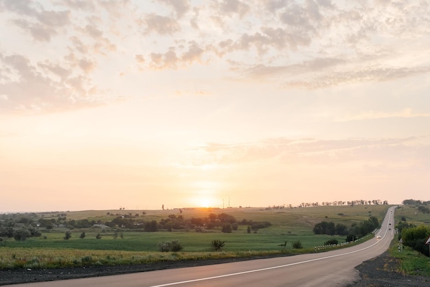 Una giovane ragazza si trova vicino a un'auto rotta in mezzo all'autostrada durante il tramonto e cerca di chiamare aiuto al telefono e avviare l'auto in attesa di aiuto servizio auto guasto auto sulla strada