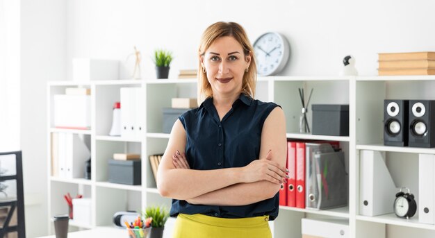 A young girl stands in the office and folded her hands  her chest.