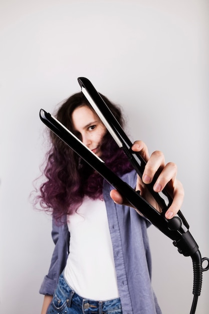 Young girl straightens curly hair of Flat Iron