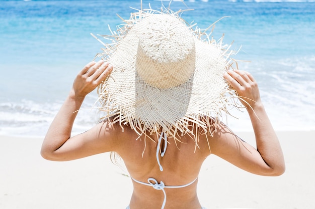 Young girl in a straw hat on the beach