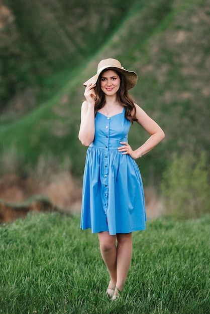 Young girl in a straw hat with large brim on mountain green slopes