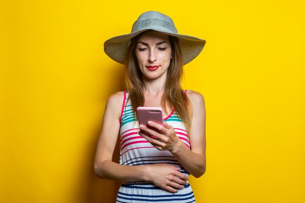 Young girl in a striped dress and hat looking at the phone 