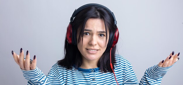 A young girl in a striped vest is listening to music in red headphones in a studio and dancing