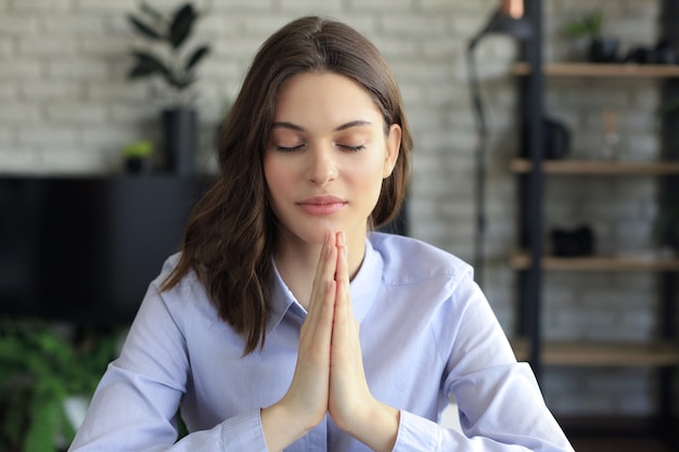 Giovane studentessa che piega le mani, pregando dio per buona fortuna. preoccupata religiosa giovane donna d'affari che chiede aiuto.