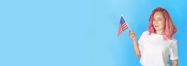 Young girl student holds american small flag on blue background, happy woman holding USA flag. wide banner