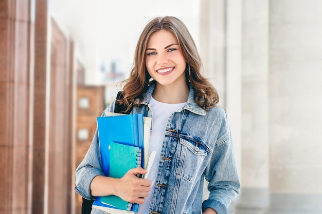 Young girl student smiling against university. 