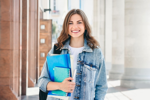 若い女子学生が大学に対して笑顔します。