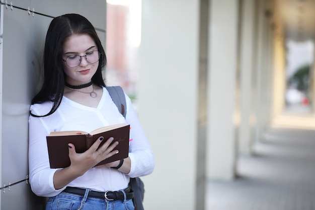 バックパックと本を持って路上で若い女の子の学生