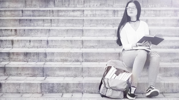 Young girl student on the street with a backpack and books