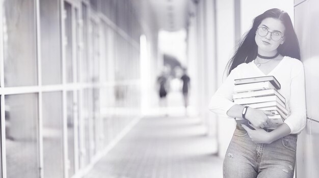 Young girl student on the street with a backpack and books