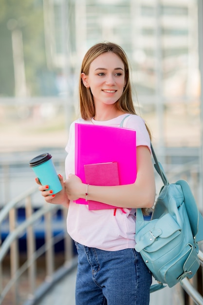 路上でコーヒーのカップを持つ若い女子生徒