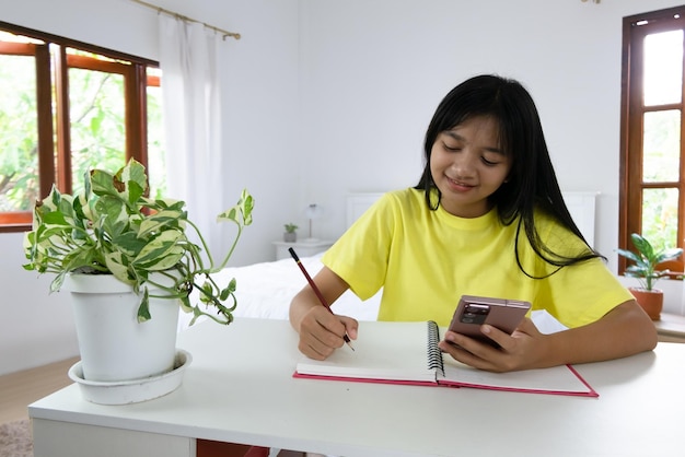 自宅で勉強している若い女の子自宅の寝室で宿題をしている学生の女の子